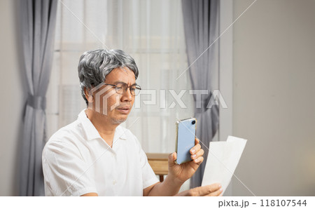 Senior man is paying bills via mobile phone. The bill payment is successful. 118107544