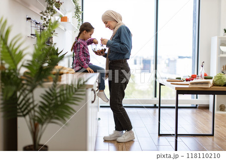 Muslim mother and daughter eating healthy salad at home 118110210