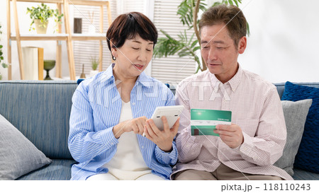 通帳を見て悩むシニア夫婦 118110243