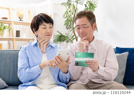 通帳を見て悩むシニア夫婦 118110244