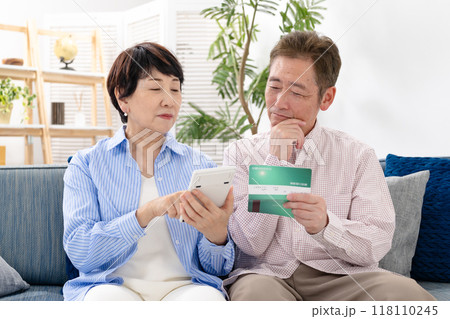通帳を見て悩むシニア夫婦 118110245