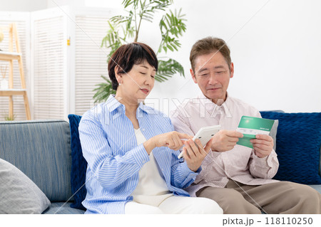 通帳を見て悩むシニア夫婦 118110250