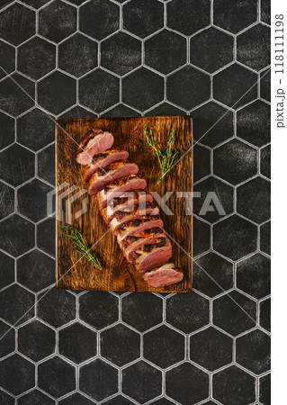 Top view of a seared duck breast cut on slices on wooden chopping board 118111198