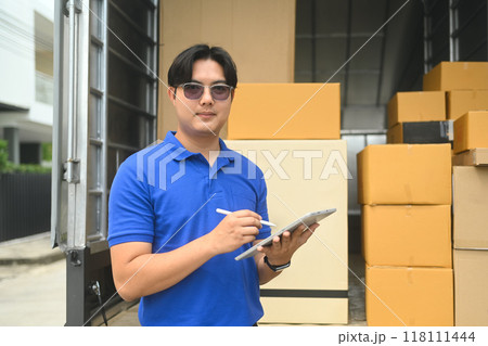 Smiling courier man with digital tablet standing near a delivery van full of cardboard boxes. Shipping service concept Smiling courier man with digital tablet standing near a delivery van full of cardboard boxes. Shipping service concept 118111444