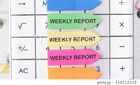 Conceptual weekly report symbol. Copy space. WEEKLY REPORT words written on the arrow-shaped stickers on the calculator 118112319