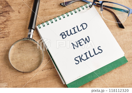 Business, education build new skills concept. Copy space. Concept word BUILD NEW SKILLS in a notebook on a papyrus background, top view 118112320