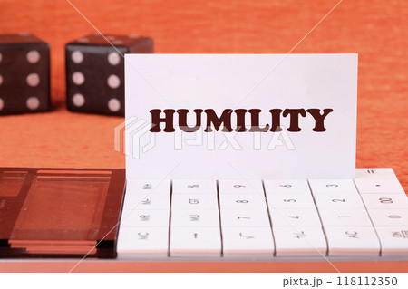 Lifestyle concept. HUMILITY word on a white business card on the calculator, front view Lifestyle concept. HUMILITY word on a white business card on the calculator, front view 118112350