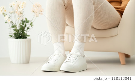 Woman Resting with Elevated Swollen Ankle on Couch in Living Room 118113041