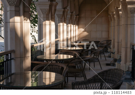 Tables, Chairs, Courtyard - Outdoor Seating Area With Sunlight Streaming Through Columns In A Historic Building. Tables, Chairs, Courtyard - Outdoor Seating Area With Sunlight Streaming Through Columns In A Historic Building. 118114483