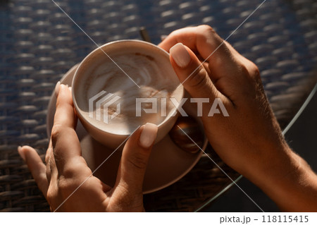 Hands, Coffee, Cafe: A person enjoying a cup of cappuccino at a cafe table. 118115415