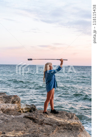 Woman, Microphone, Beach - A woman holding a microphone stands on a rocky beach overlooking the ocean during a sunset. Woman, Microphone, Beach - A woman holding a microphone stands on a rocky beach overlooking the ocean during a sunset. 118115438