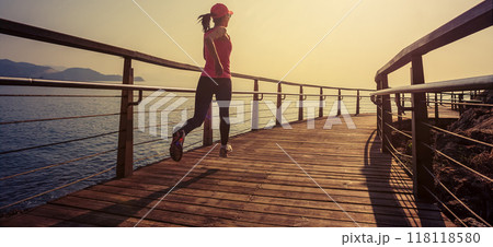 Healthy lifestyle sports woman running on wooden boardwalk seaside 118118580