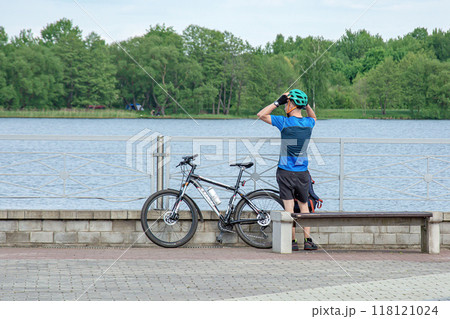 Belarus, Minsk - May 28, 2021: A cyclist is resting on the observation deck on the embankment Belarus, Minsk - May 28, 2021: A cyclist is resting on the observation deck on the embankment 118121024