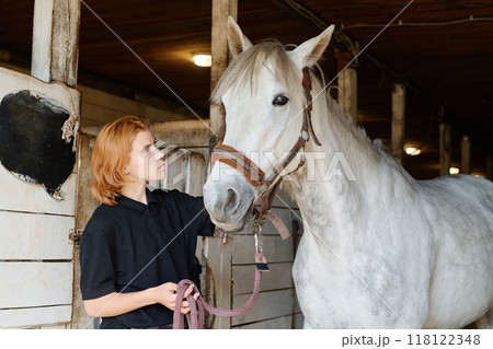 Caring for Horse in Rustic Stable Setting 118122348