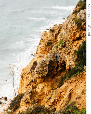 Steep, rugged cliffs overlooking the ocean, with textured rock formations and sparse vegetation Steep, rugged cliffs overlooking the ocean, with textured rock formations and sparse vegetation 118124285