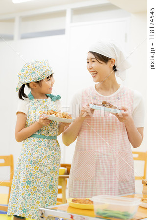 エプロンをして料理する母娘 118124545