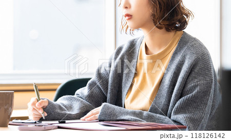 真剣な表情でメモを取る女性 真剣な表情でメモを取る女性 118126142