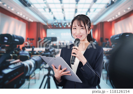 記者会見場からレポートをする女性記者 118126154
