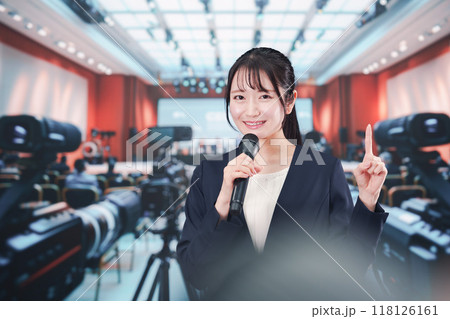 記者会見場からレポートをする女性記者 118126161