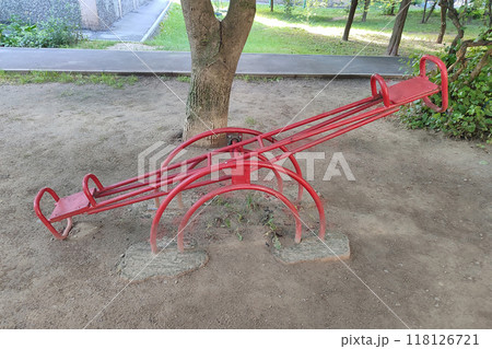 An old red swing for two in the yard near the house. An old red swing for two in the yard near the house. 118126721