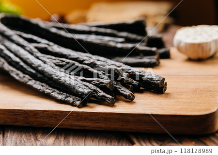 Rustic black meat sticks with herbs and spices on board, perfect for gourmet and food photography 118128989