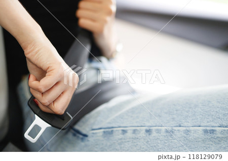 Close Up of people business woman hand fastening seat safety belt in car for safety before driving on the road. concept transport travel. soft focus. Close Up of people business woman hand fastening seat safety belt in car for safety before driving on the road. concept transport travel. soft focus. 118129079