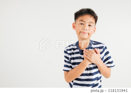 Happy young kid boy in casual clothes holding hands at chest close to heart meditation and smiling in studio short isolated on white background, primary child believe faith and love gratitude Happy young kid boy in casual clothes holding hands at chest close to heart meditation and smiling in studio short isolated on white background, primary child believe faith and love gratitude 118131941