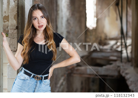 Young woman in jeans and black tee shirt posing in ruined building 118132343