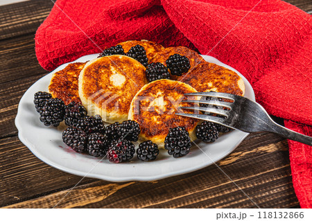 Cottage cheese pancakes with fresh blackberries on a white flat white plate 118132866