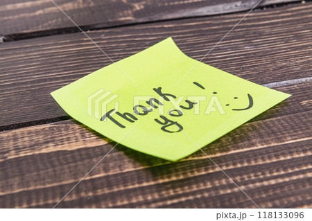 Thank you word with emoticon on green paper on wooden table Thank you word with emoticon on green paper on wooden table 118133096
