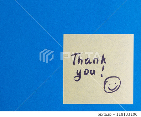 The word thank you with a smiley face on a yellow leaf on a blue background The word thank you with a smiley face on a yellow leaf on a blue background 118133100