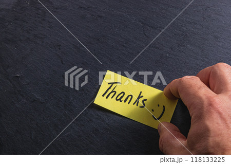 The man is holding a piece of paper with the word thank you in his right hand 118133225