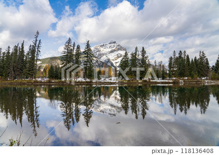 Banff National Park beautiful natural scenery. Cascade Mountain with blue sky, white clouds reflected on Bow River like a mirror in a snowy autumn sunny day. Town of Banff, Canadian Rockies. 118136408