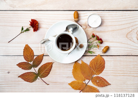 Autumn, fall leaves, hot steaming cup of coffee and a warm scarf on wooden table background. Seasonal, morning coffee, Sunday relaxing and still life concept. 118137128