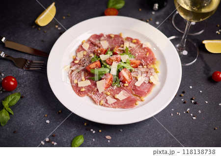 cooking tuna carpaccio - cherry tomato pieces on a plate with raw tuna fillet slices cooking tuna carpaccio - cherry tomato pieces on a plate with raw tuna fillet slices 118138738