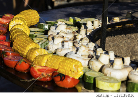 A person wearing black gloves is preparing food on a grill outdoors 118139816