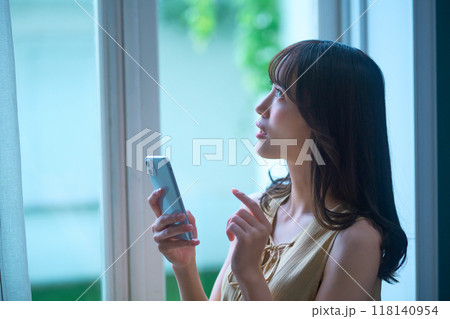 部屋でスマホを操作する若い女性のライフスタイルイメージ 部屋でスマホを操作する若い女性のライフスタイルイメージ 118140954
