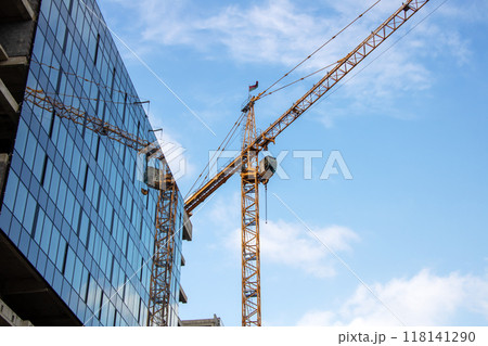 During the day, a crane is seen in front of a building under construction During the day, a crane is seen in front of a building under construction 118141290