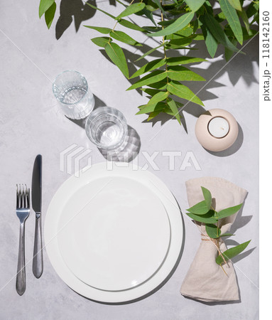 Festive table setting with white plates, glasses and candle for a celebration with eucalyptus 118142160
