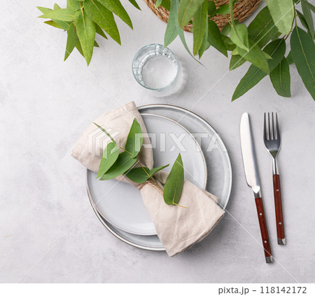 Festive table setting with two plates and glass for a celebration with eucalyptus branches  118142172