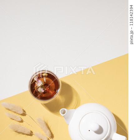 Creative layout of a glass cup of herbal tea with flowers and fruits and teapot  118142394