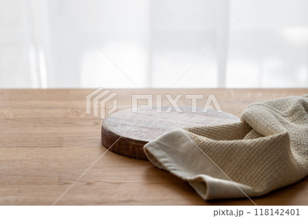 Empty cutting board on wooden texture tabletop with kitchen towel in front of window. 118142401