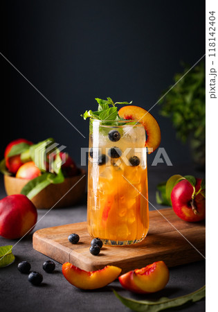 Peach tea with ice, mint and blueberry on tall glass. Vegan homemade cold healthy drink Peach tea with ice, mint and blueberry on tall glass. Vegan homemade cold healthy drink 118142404