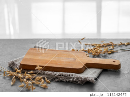 Empty cutting board on a blue textured background in front of a window with a dry branch  118142475