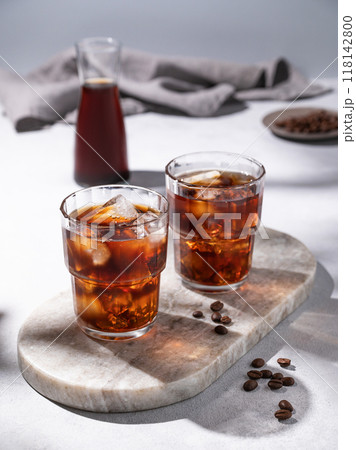 Cold brew coffee in a two glasses with ice on a marble board on a light background with coffee beans 118142800
