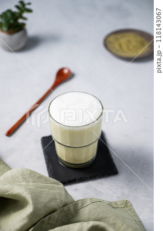 Matcha latte with ice. Green tea with milk in a glass on a light background with spoon, napkin.  118143067