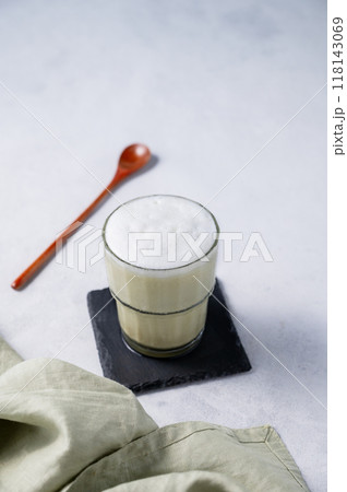 Matcha latte with ice. Green tea with milk in a glass on a light background with spoon and napkin. Matcha latte with ice. Green tea with milk in a glass on a light background with spoon and napkin. 118143069