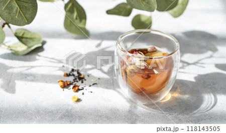 Glass of herbal tea on gray background with morning sunlight with shadow and plant branch.  118143505