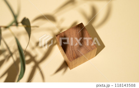 Empty wooden cube with shadows and green leaves on a yellow background with shadow Empty wooden cube with shadows and green leaves on a yellow background with shadow 118143508
