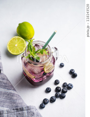 Blueberry mojito or lemonade with lime, ice and mint in a glass on a light background Blueberry mojito or lemonade with lime, ice and mint in a glass on a light background 118143520